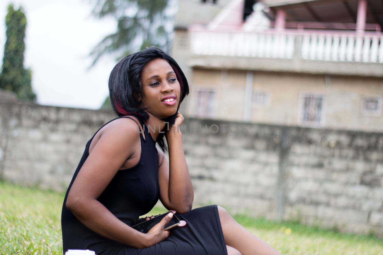 young woman sitting alone in a garden and holding a mobile phone