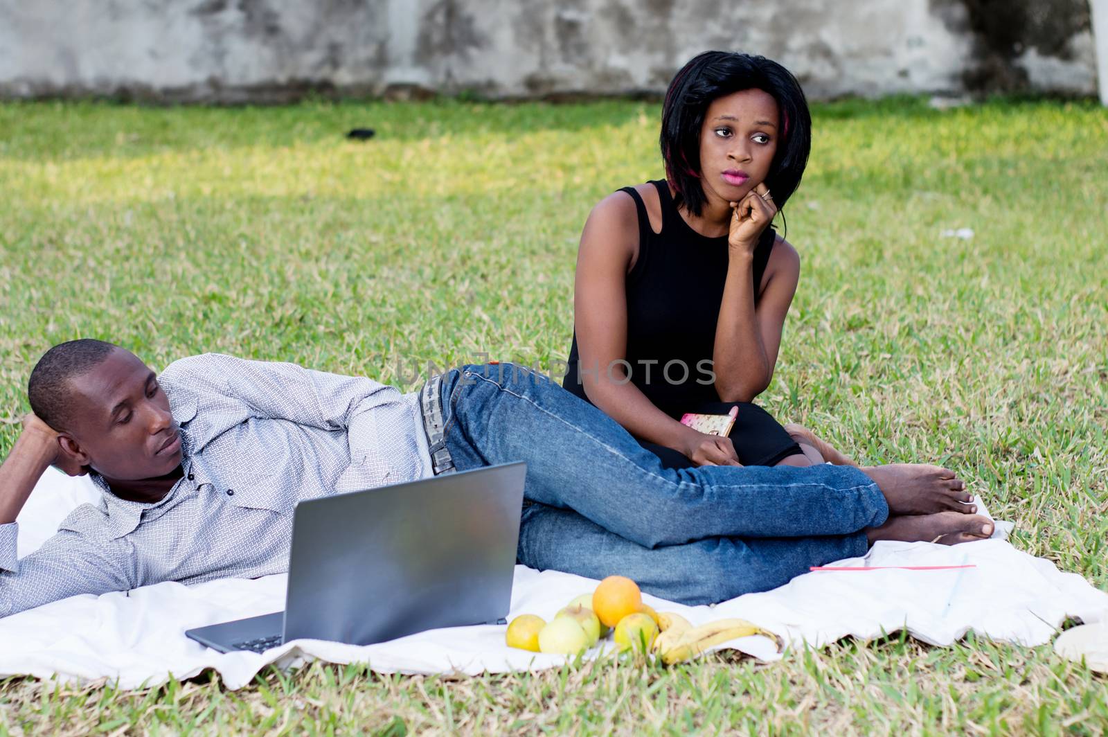 young couple sitting in the park sad and do not talk after a dispute