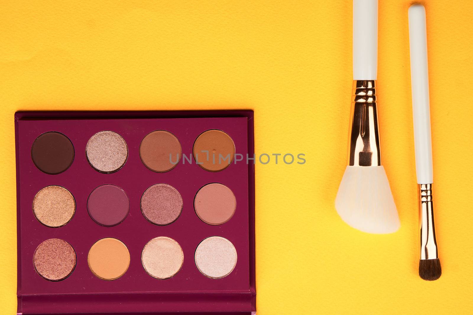 Eyeshadows and makeup brushes on a yellow background top view professional cosmetics. High quality photo