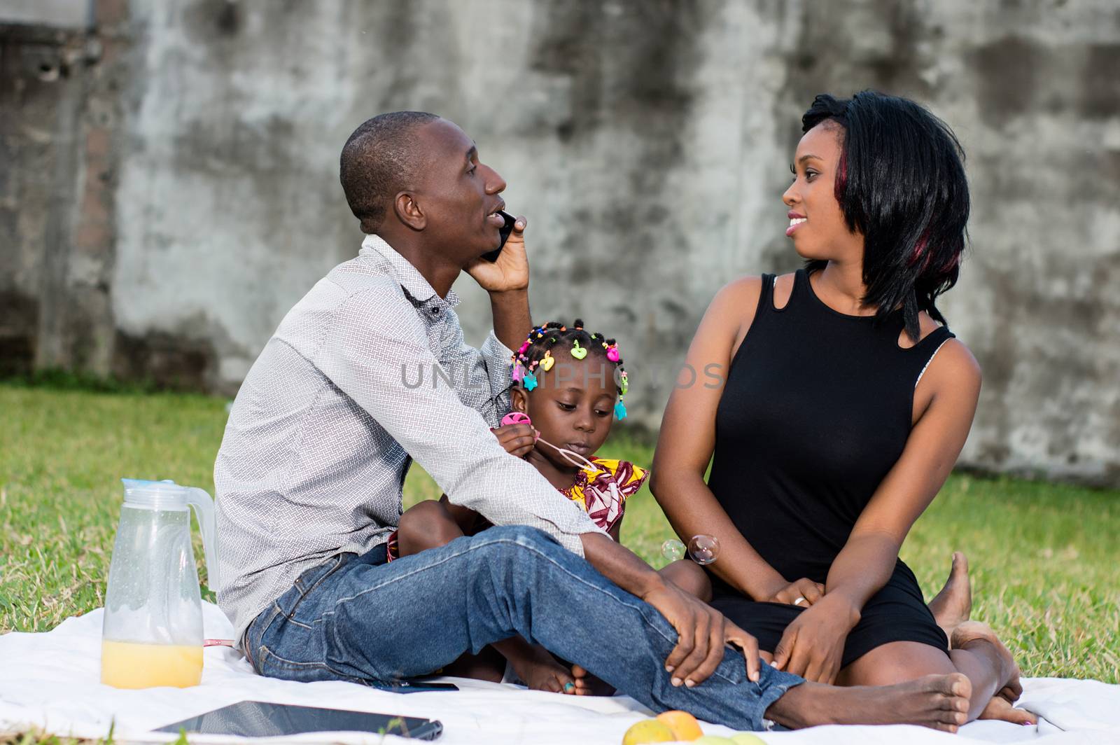 Good family sat on the grass in the park with their child and played together during the picnic