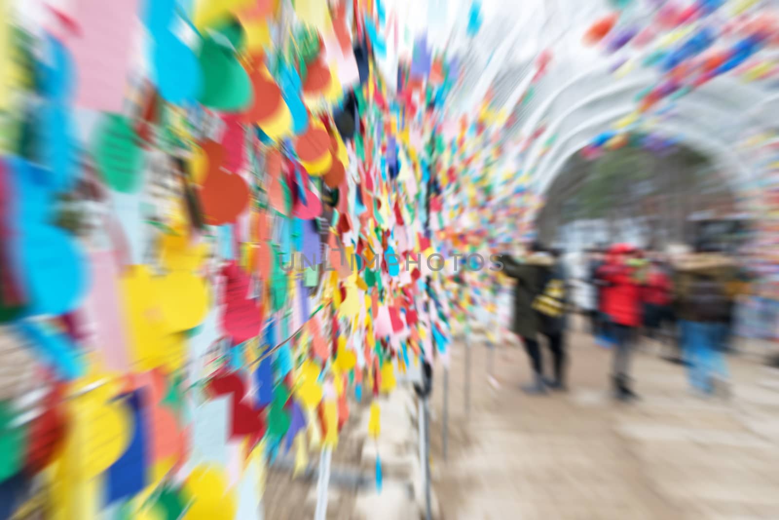 The blurred of people in the tunnel with hanging color paper notes.