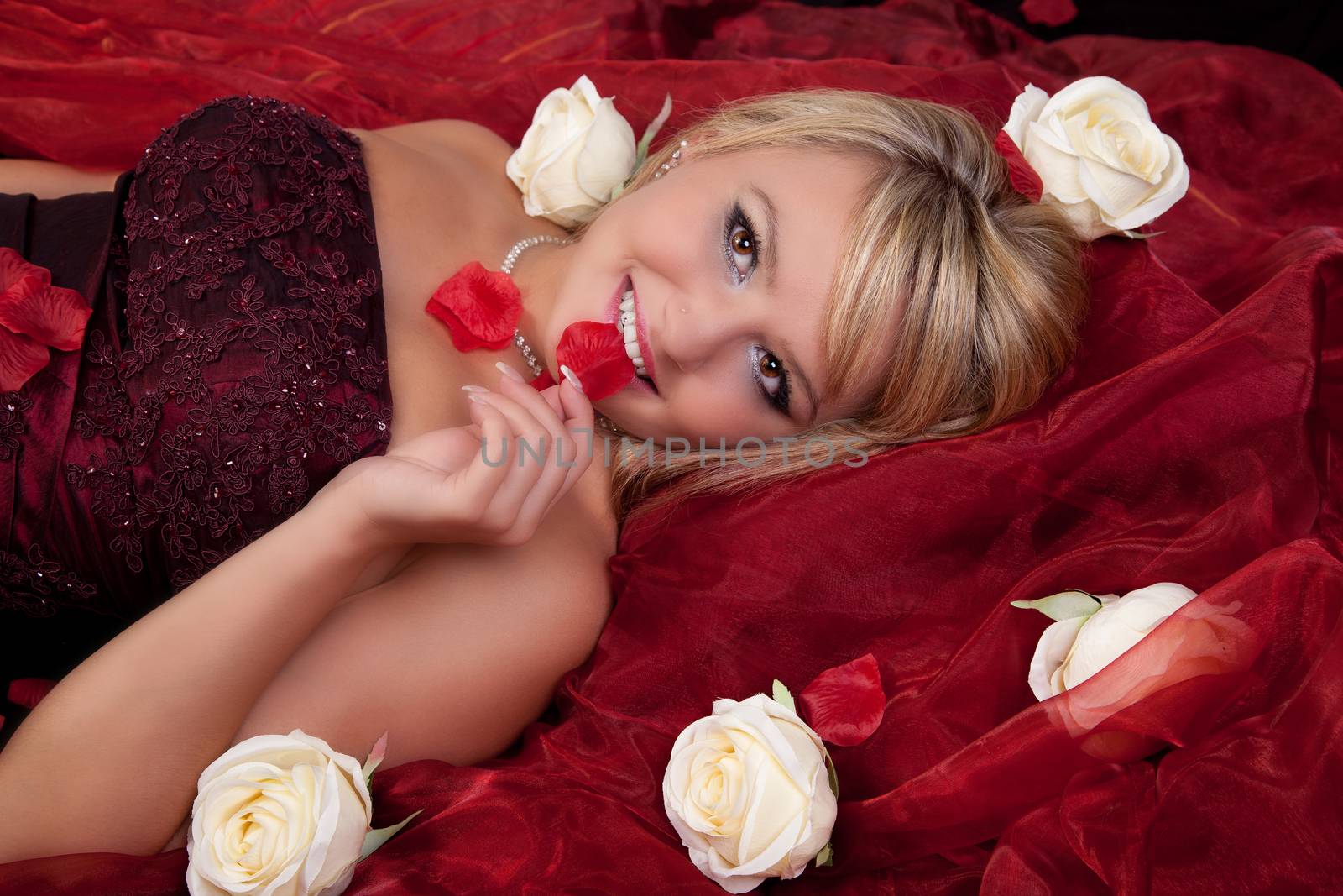 Young blonde woman is lying in roses