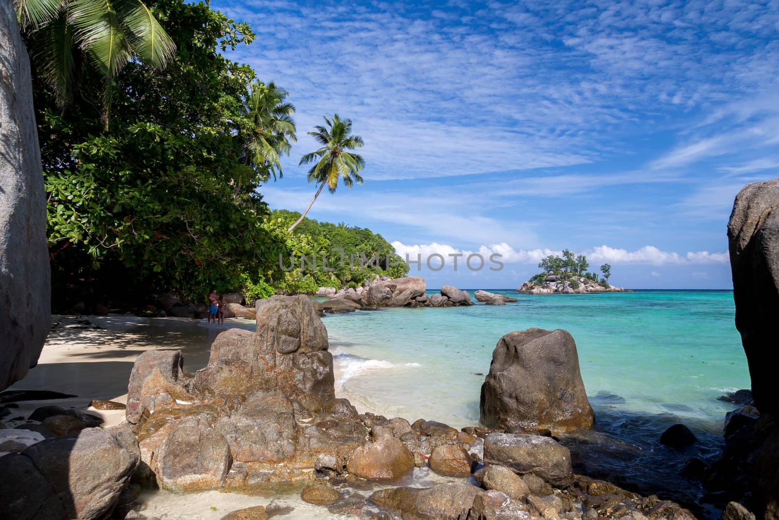 Beach with blue water and blue sky and white sand and some rocks