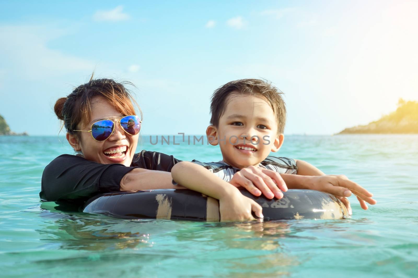 Mother and son playing in the sea and laughing happily in a weekend.