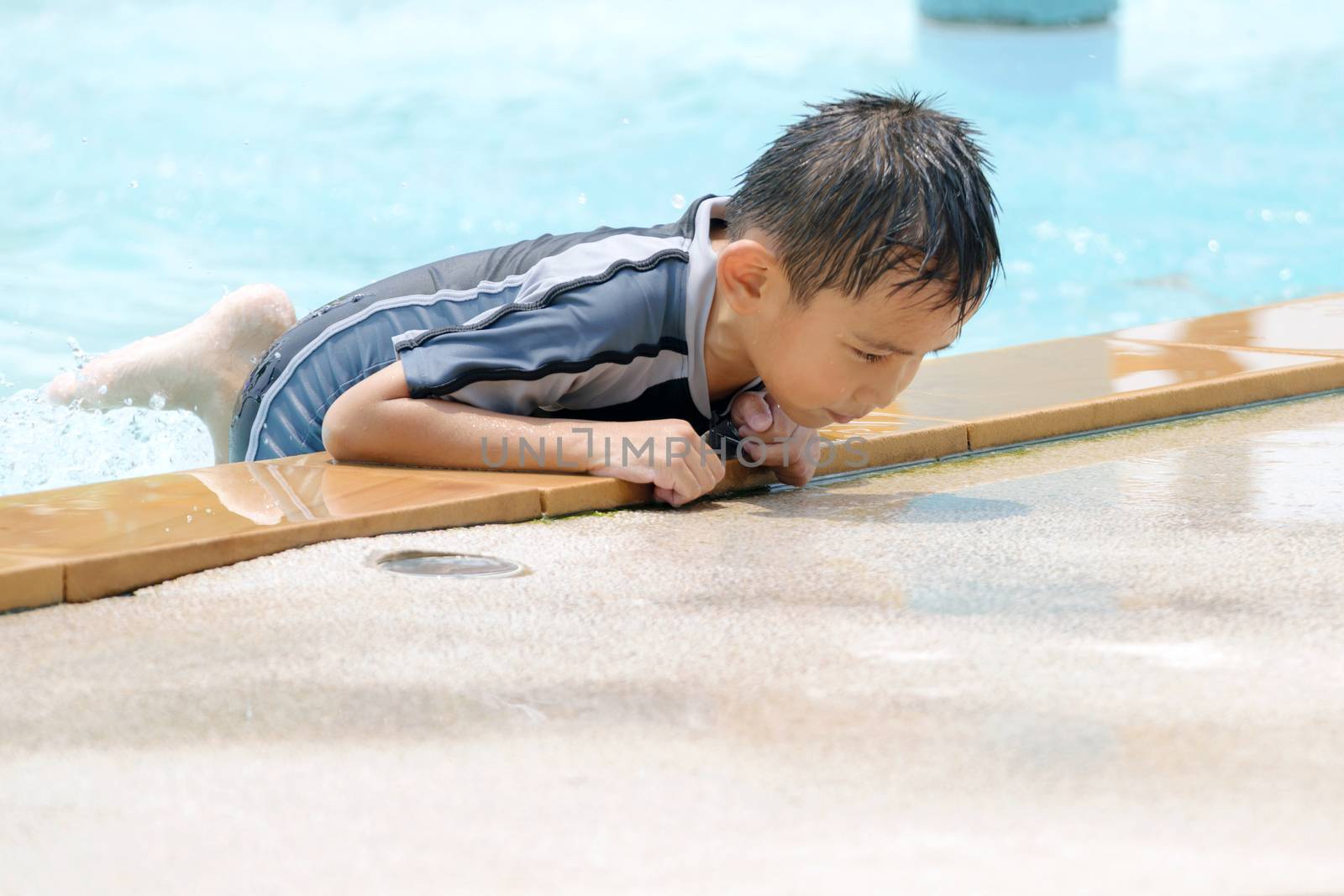 Asian boy in swimwear, swimming fun in the pool.