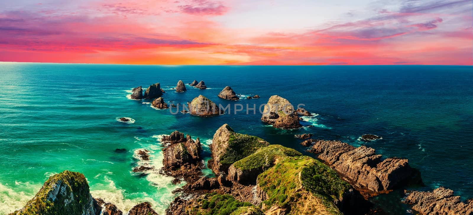 Sunset over Nugget Point which is located in the Catlins area on the Southern Coast of New Zealand. There area many rock islands - nuggets - in the sea. Panoramic photo