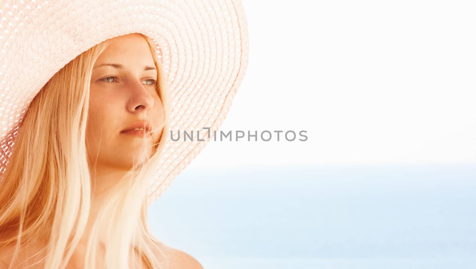 Woman with blond hair wearing hat, enjoying seaside and beach lifestyle in summertime, holiday travel and leisure concept