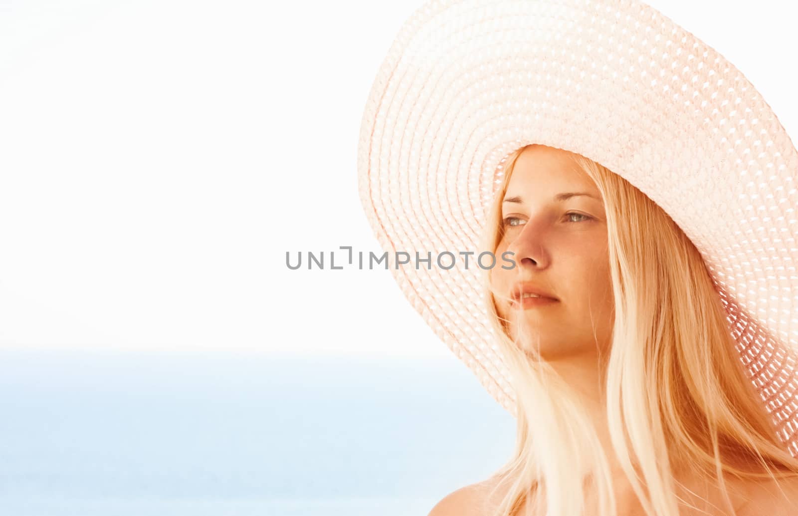 Woman with blond hair wearing hat, enjoying seaside and beach lifestyle in summertime, holiday travel and leisure concept