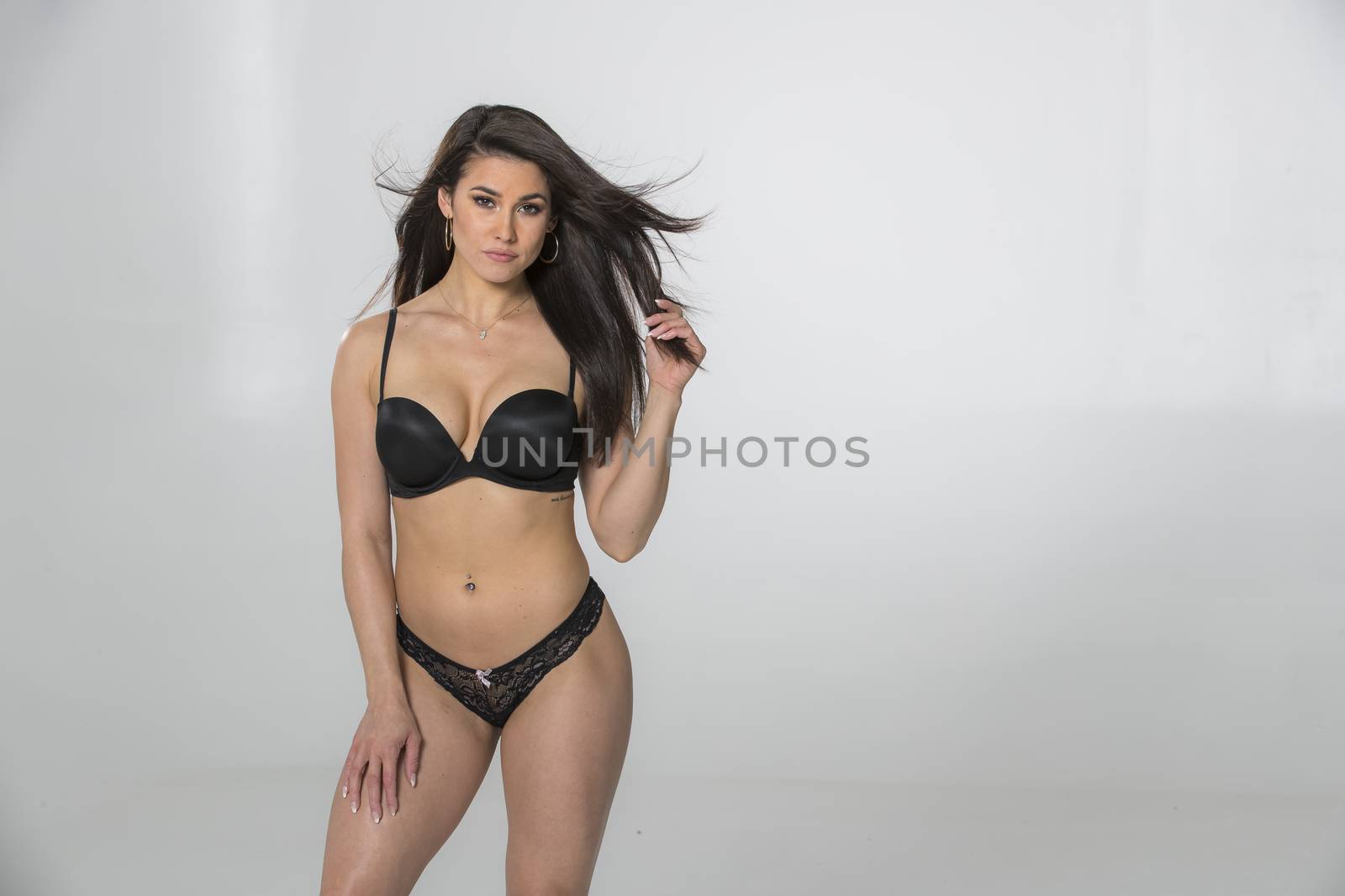 A gorgeous brunette model posing in lingerie in a studio environment