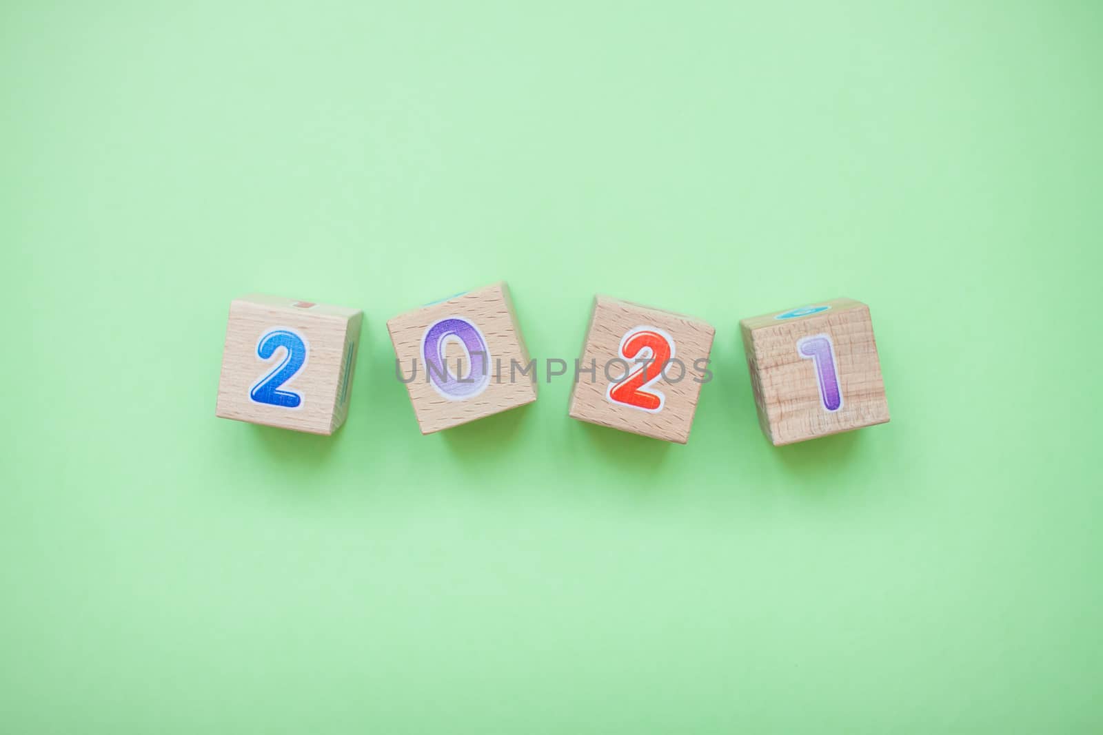 Happy New year 2021 celebration. The inscription 2021 from children's educational wooden cubes on a green background