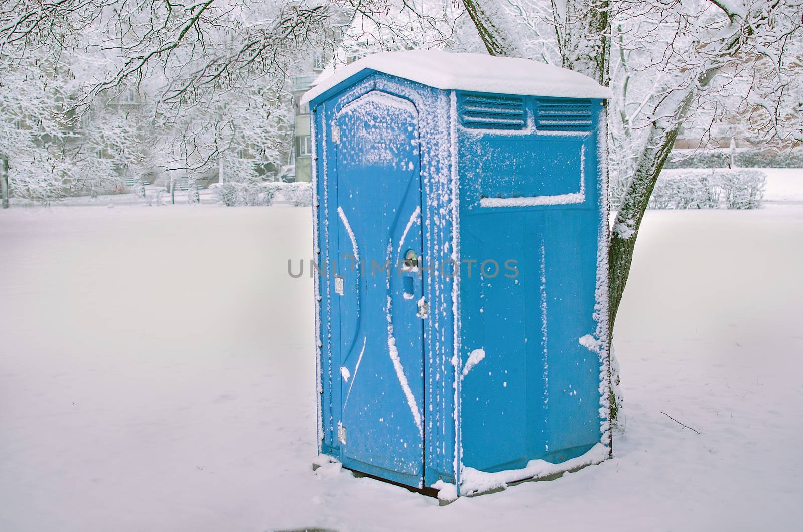 Snow covered blue cabine of bio toilets in the city center. WC. Public  plastic outdoor chemical  toilet in the park in winter time. Hiking services.