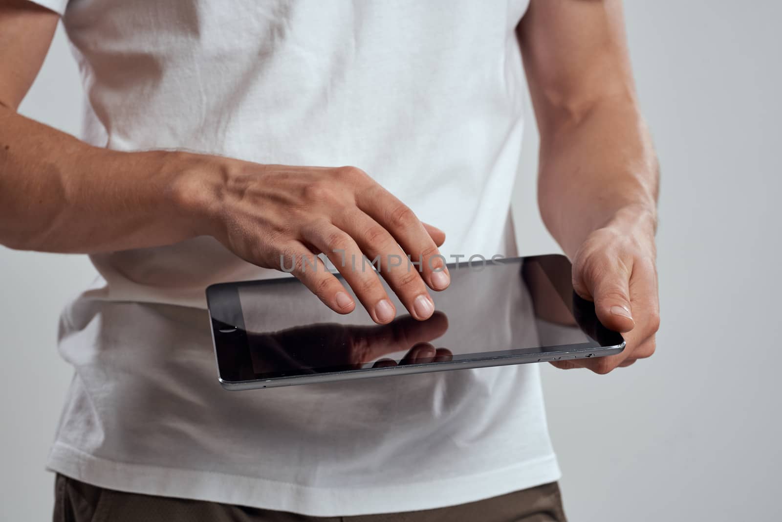 Tablet with a touch screen on a light background male hands white t-shirt cropped view by SHOTPRIME