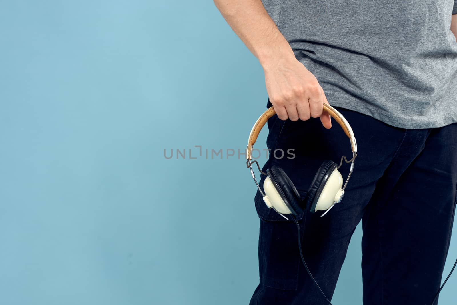 Headphones in man hands cropped view music technology blue background. High quality photo