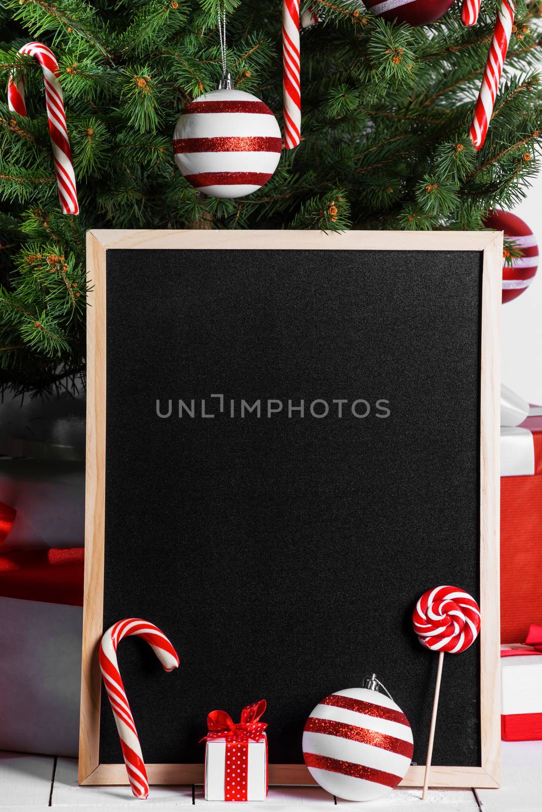 Blank blackboard and Christmas tree branches, red glass ball and candy canes