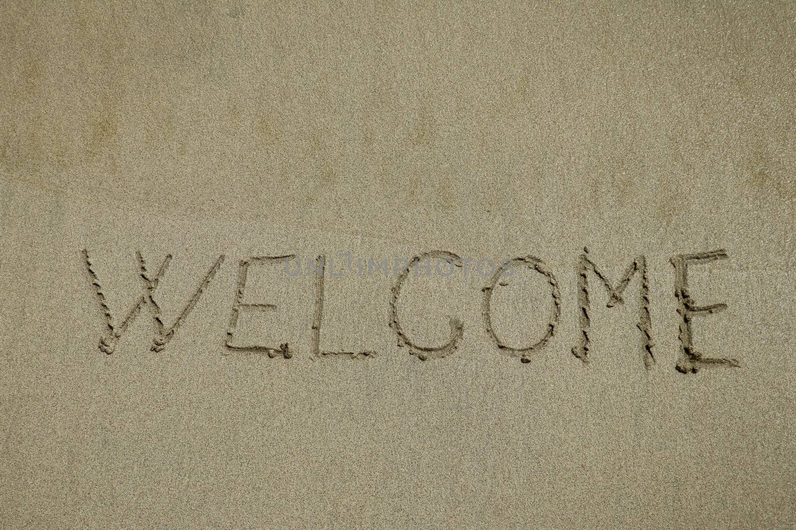 Inscription welcome on a wet sand. Welcome, texture on the beach sand.