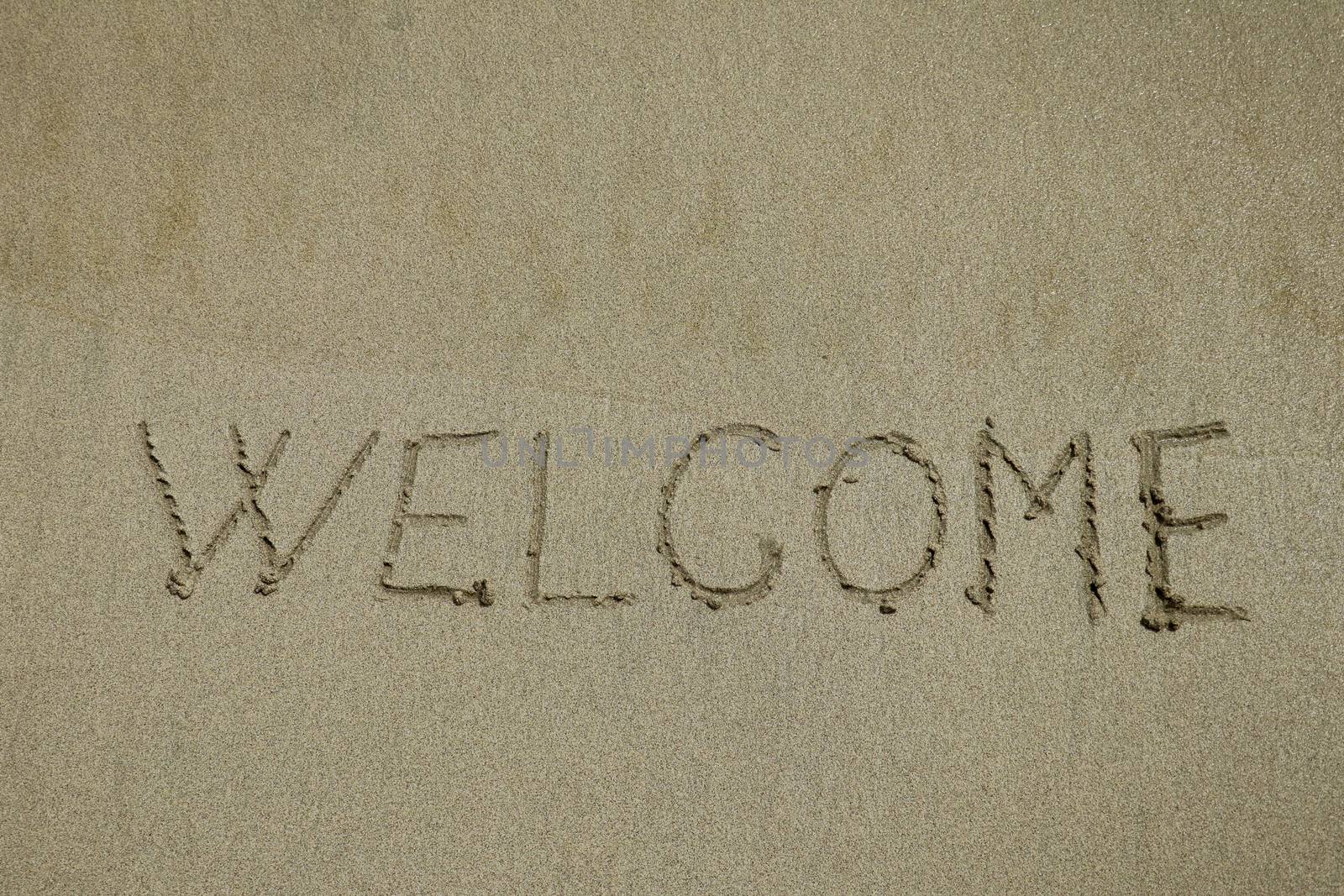 Inscription welcome on a wet sand. Welcome, texture on the beach sand.