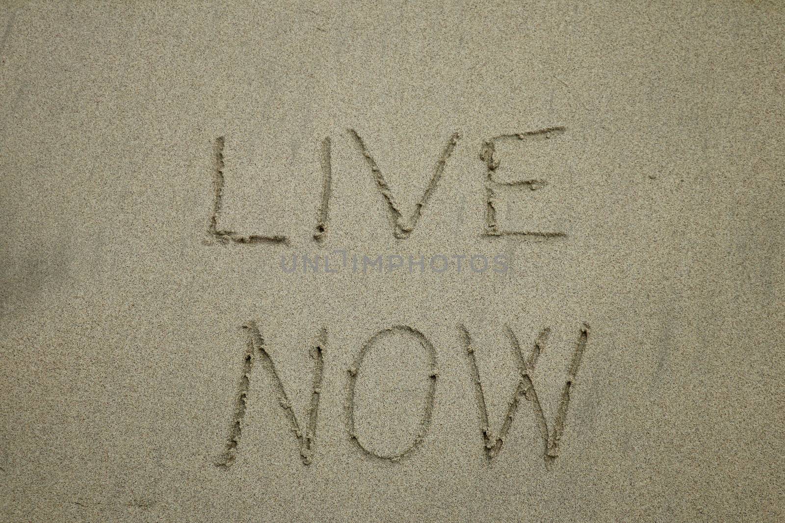 live now, mindfulness concept, text written on the sand,