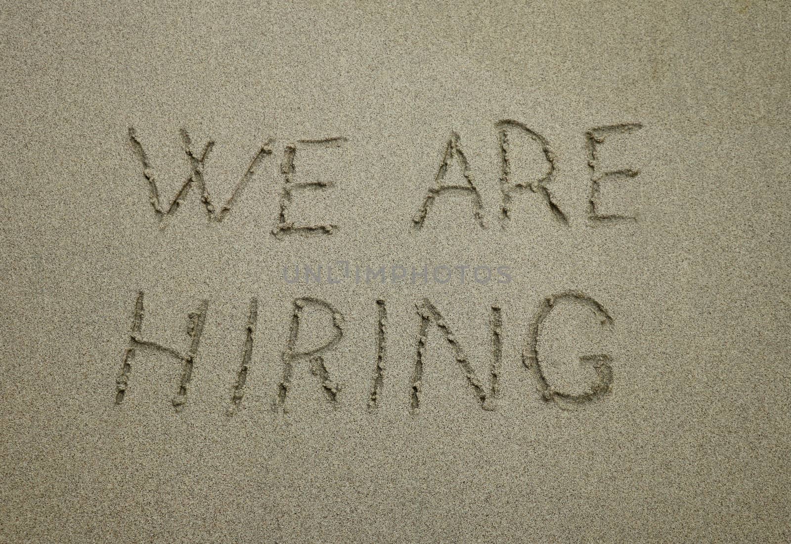 we are hiring, concept on the beach. concept text written on sand by Sanatana2008