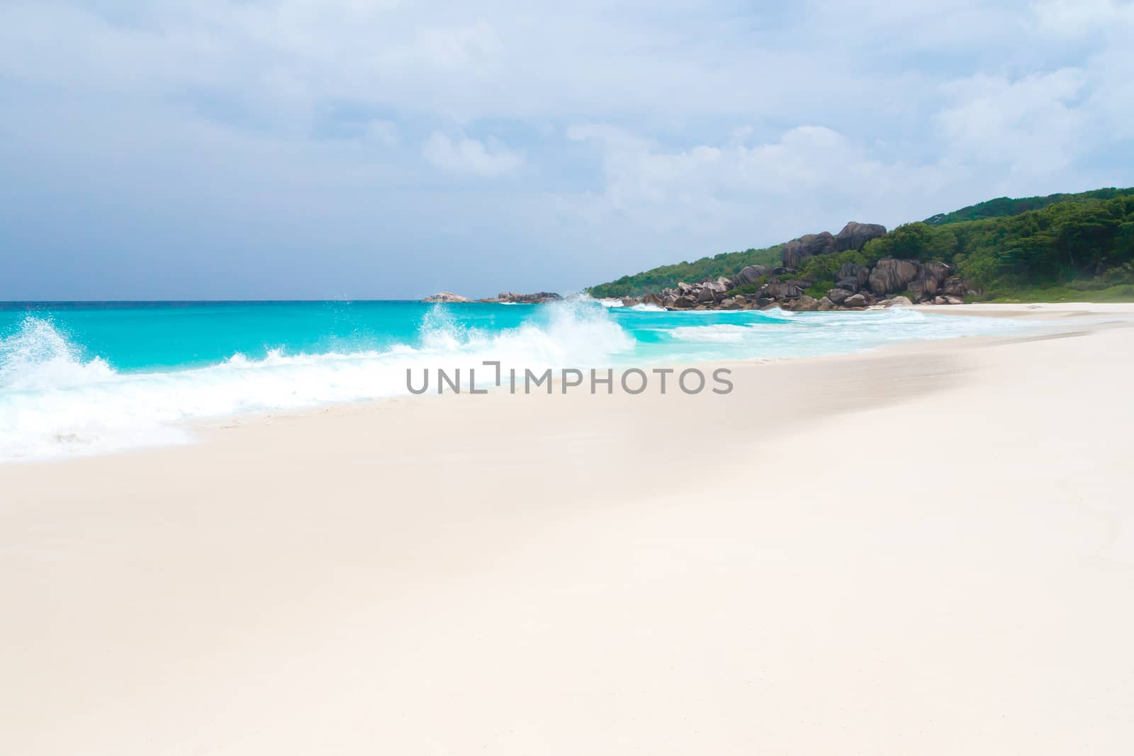 The beach on the Seychelles with white sand turquoise water and blue sky