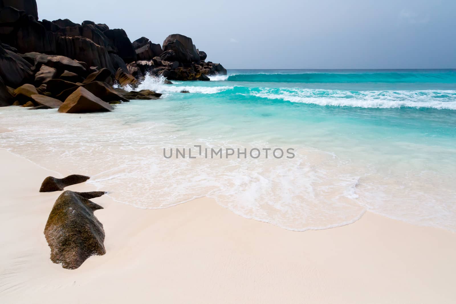 Blue sky and a white sand beach with a lot of big rocks