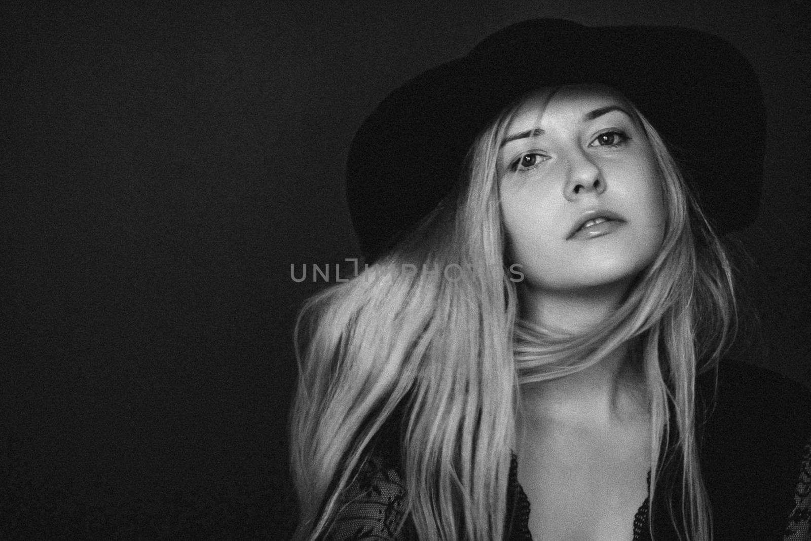 Beautiful blonde woman wearing a hat, artistic film portrait in black and white for fashion campaign and beauty brands