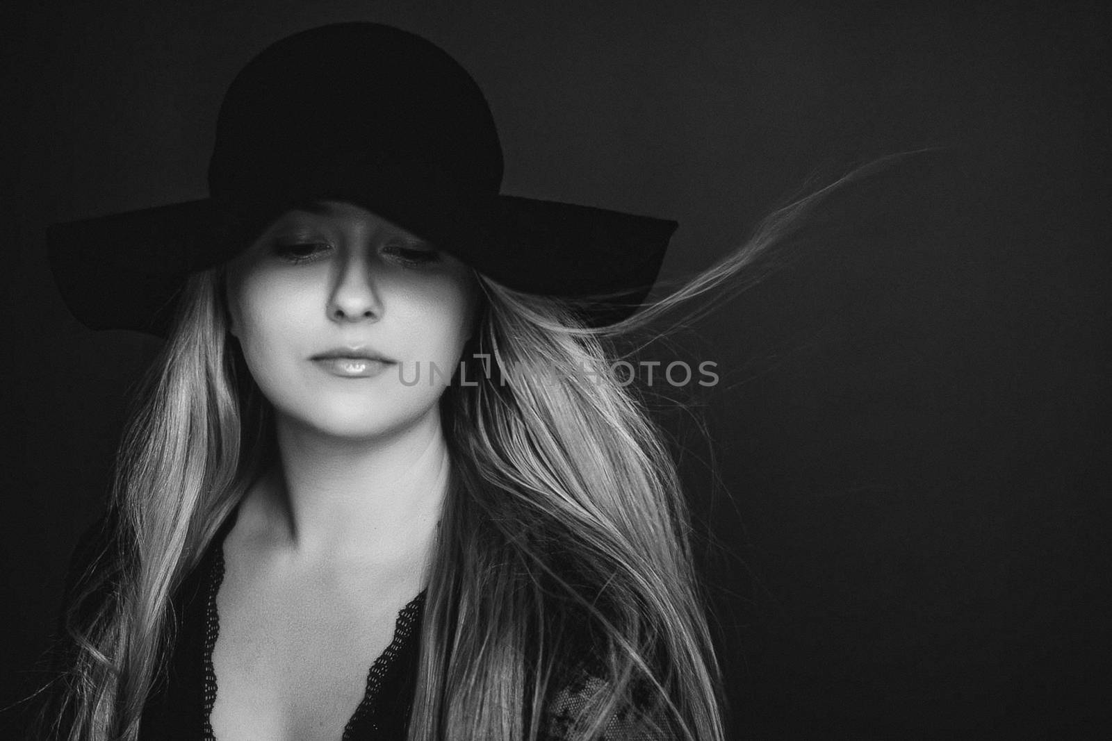 Beautiful blonde woman wearing a hat, artistic film portrait in black and white for fashion campaign and beauty brands