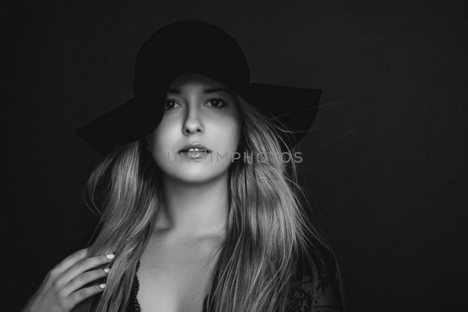 Beautiful blonde woman wearing a hat, artistic film portrait in black and white for fashion campaign and beauty brands