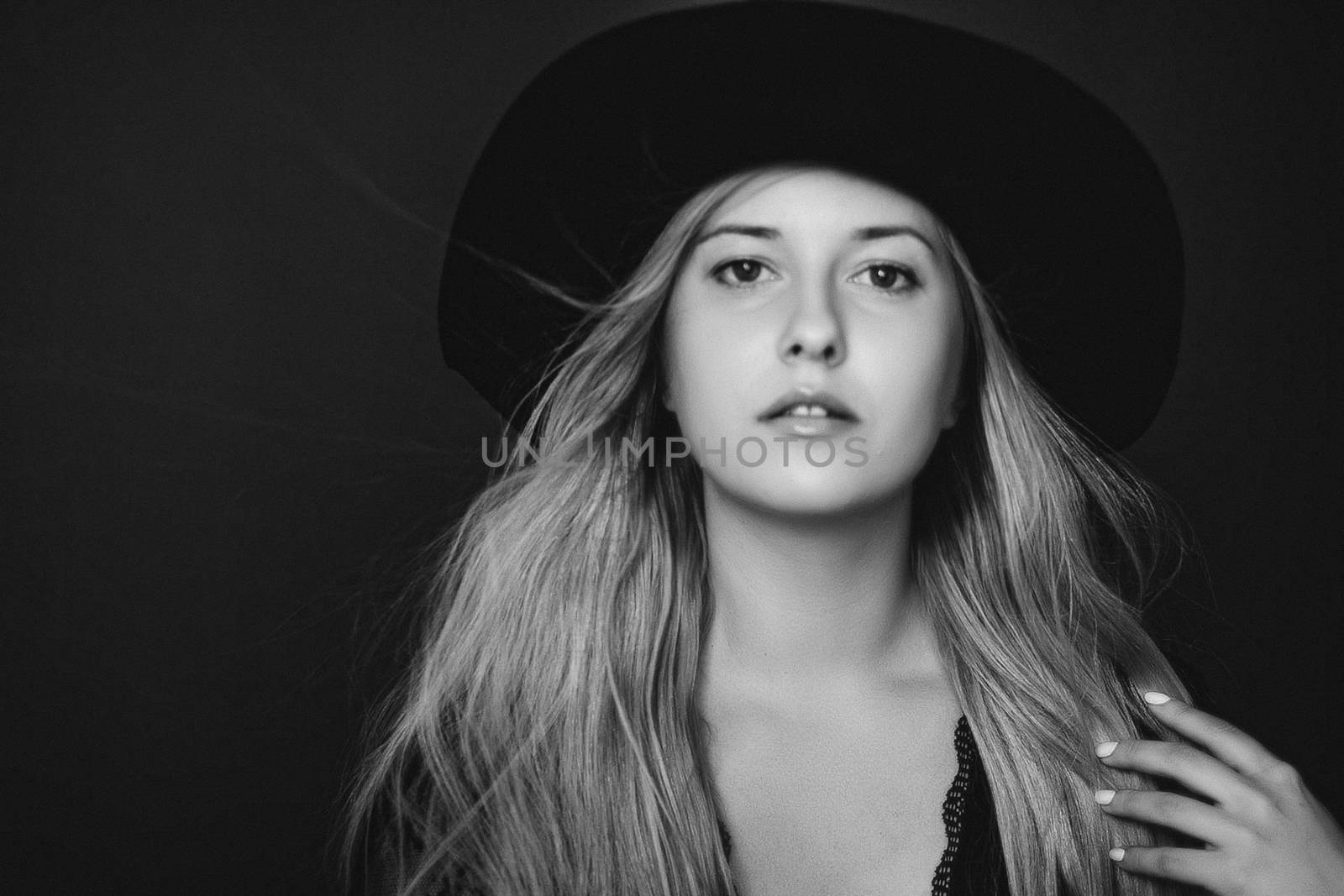 Beautiful blonde woman wearing a hat, artistic film portrait in black and white for fashion campaign and beauty brands