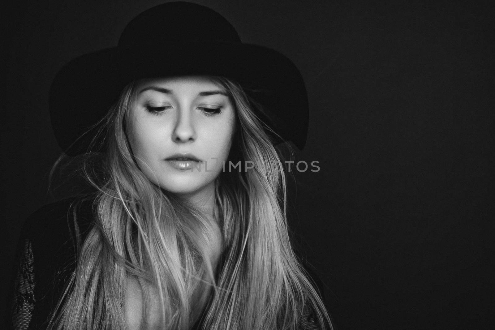 Beautiful blonde woman wearing a hat, artistic film portrait in black and white for fashion campaign and beauty brands