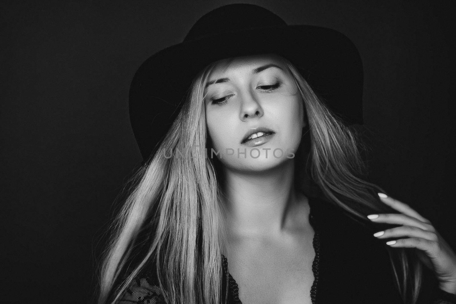 Beautiful blonde woman wearing a hat, artistic film portrait in black and white for fashion campaign and beauty brands