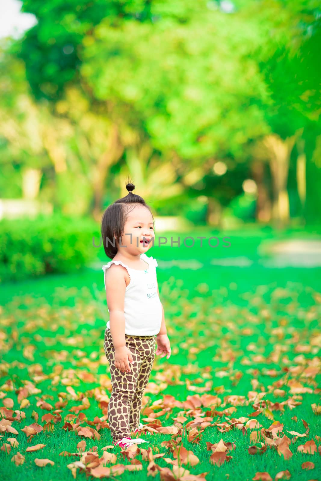 child girl standing in the park and smiling happy