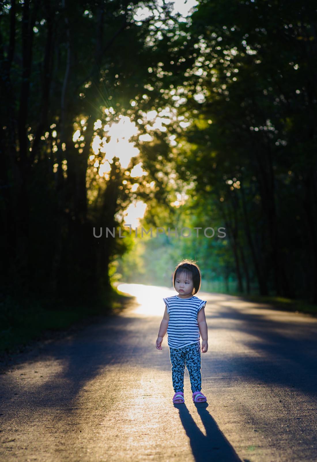 child girl standing on the road in the evening