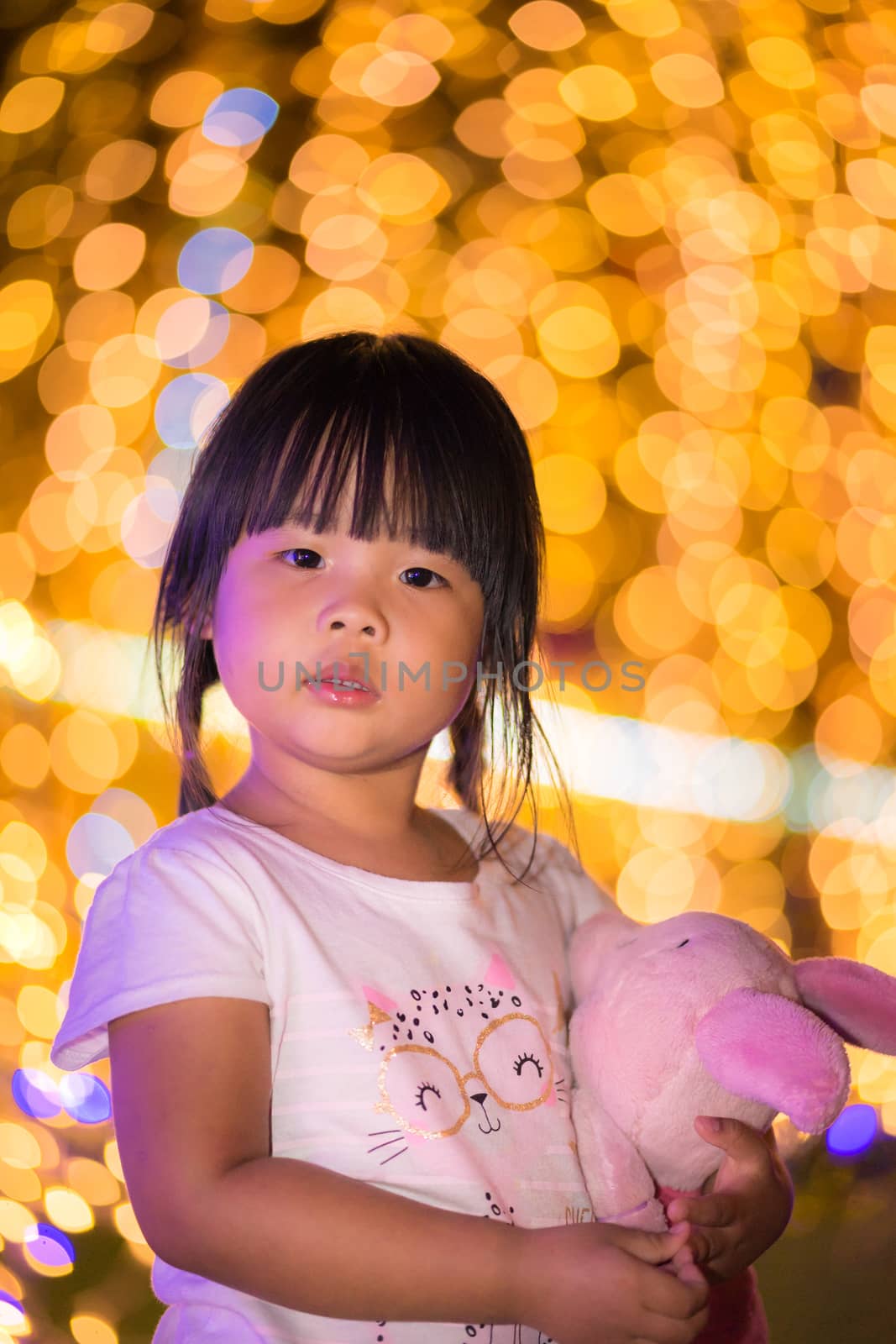little asian girl hug doll and bokeh background on Christmas day