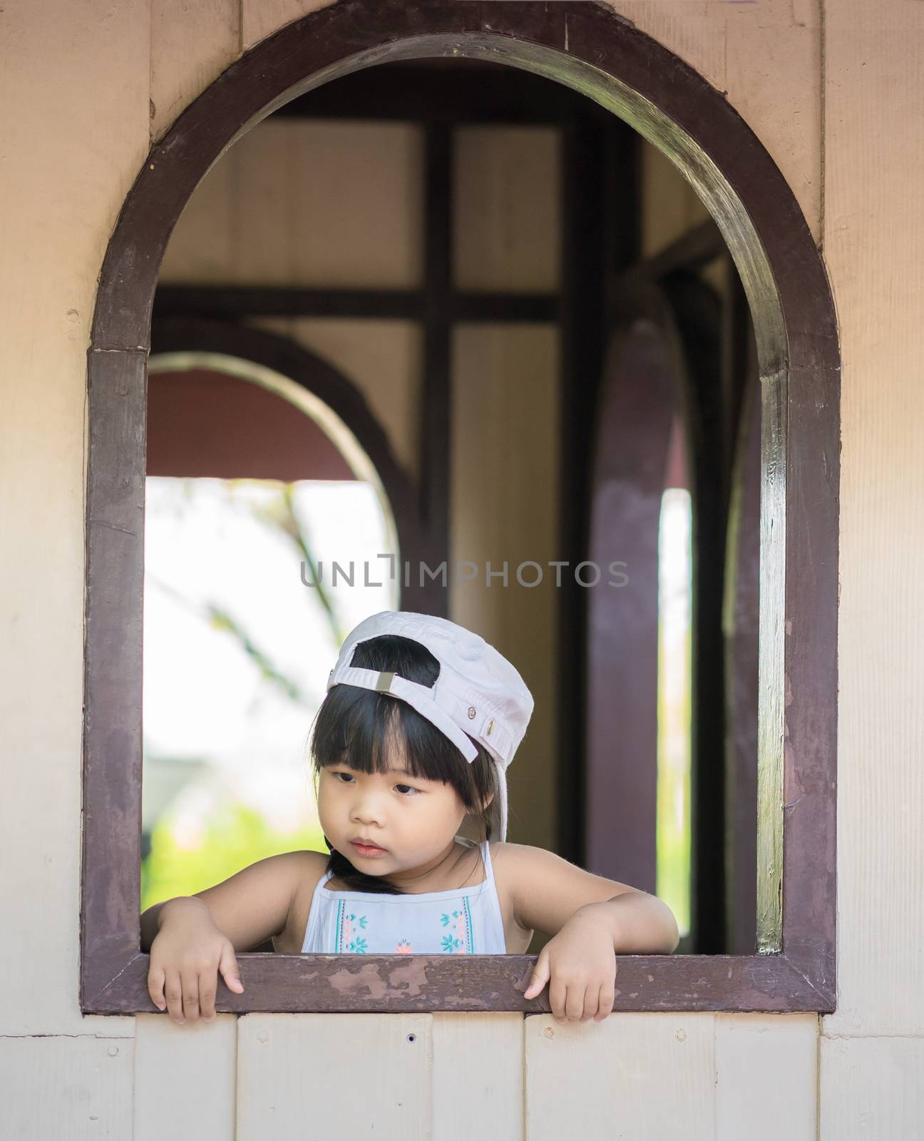 little girl wear hat standing by the window