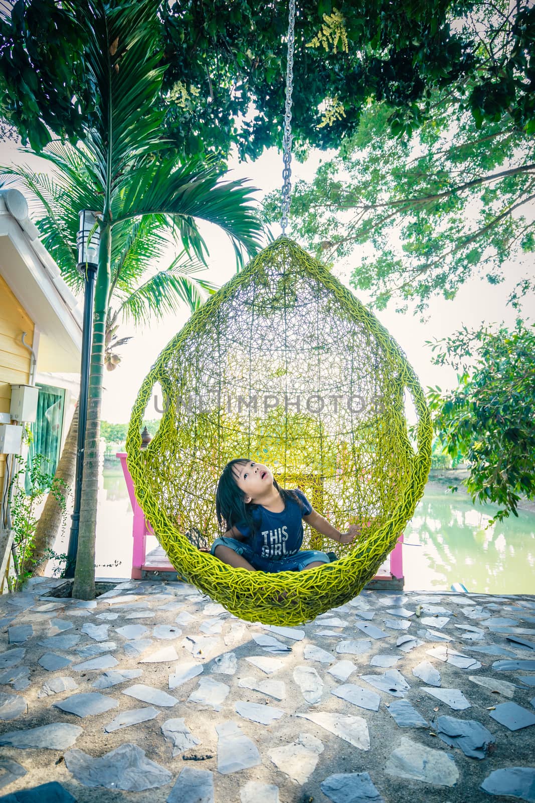 little asian girl sitting on cradle near the river