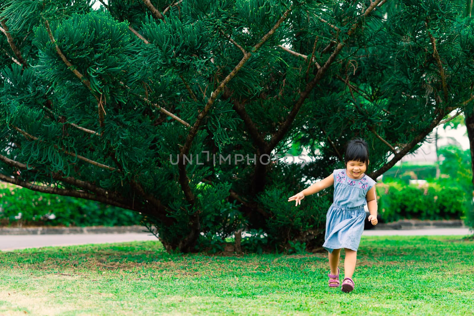 Happy little girl in dress running in the park