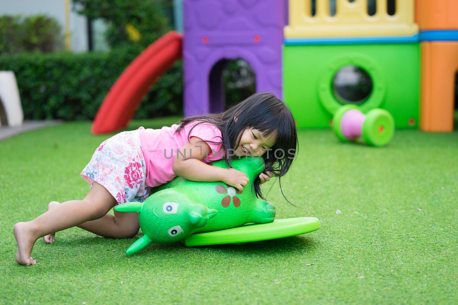Asian little girl enjoys playing in a children playground by domonite
