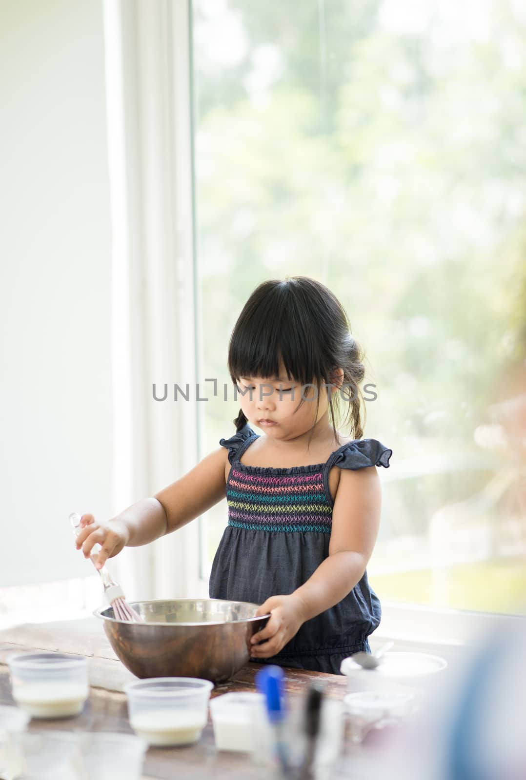 Asian little girl cooking something in kitchen