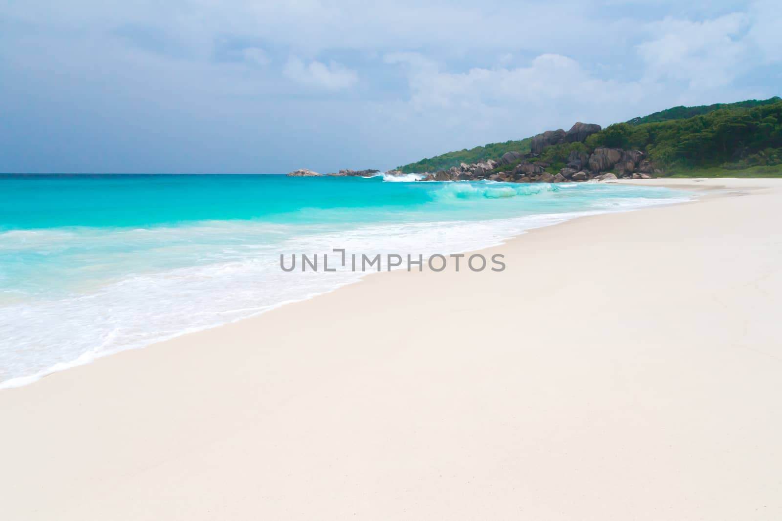 The beach on the Seychelles with white sand turquoise water and blue sky