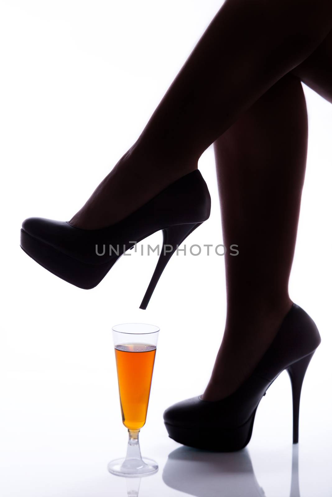 Legs of a woman in high heels over a wine glass