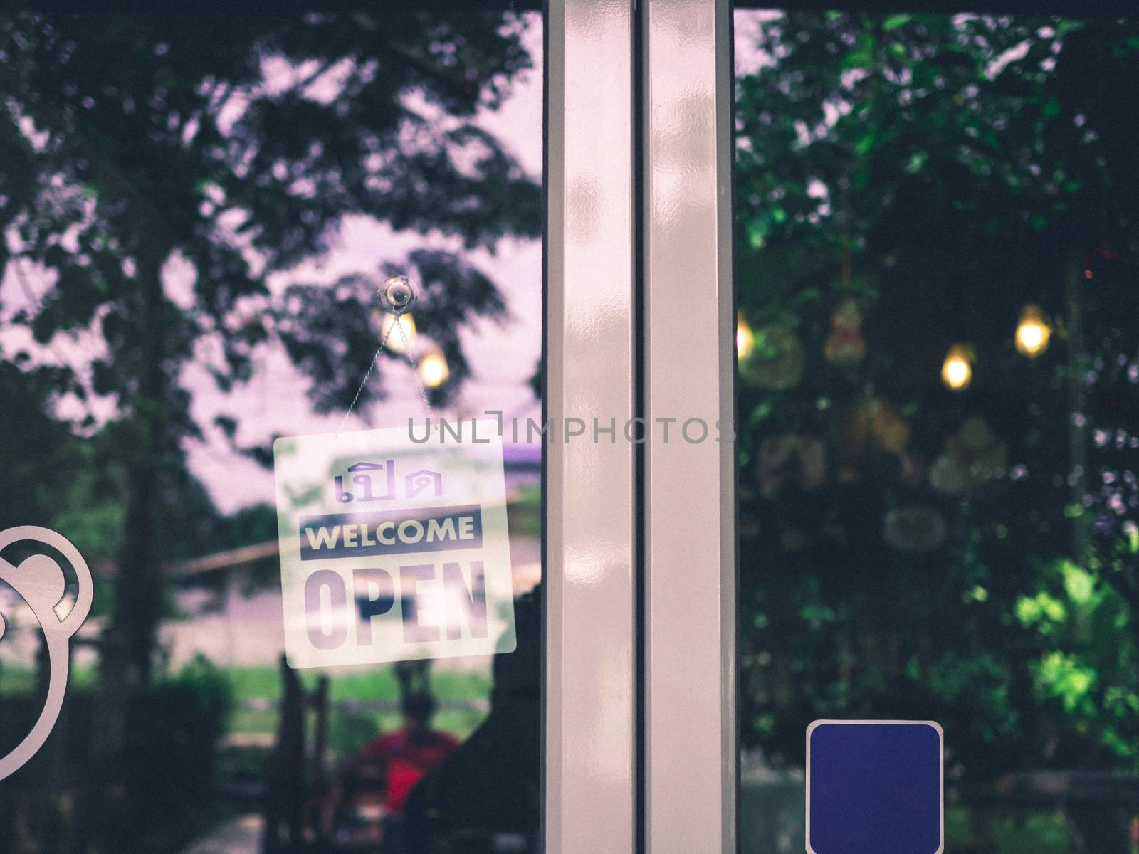 An open sign hangs behind the glass of a shop door. The idea of  by Unimages2527