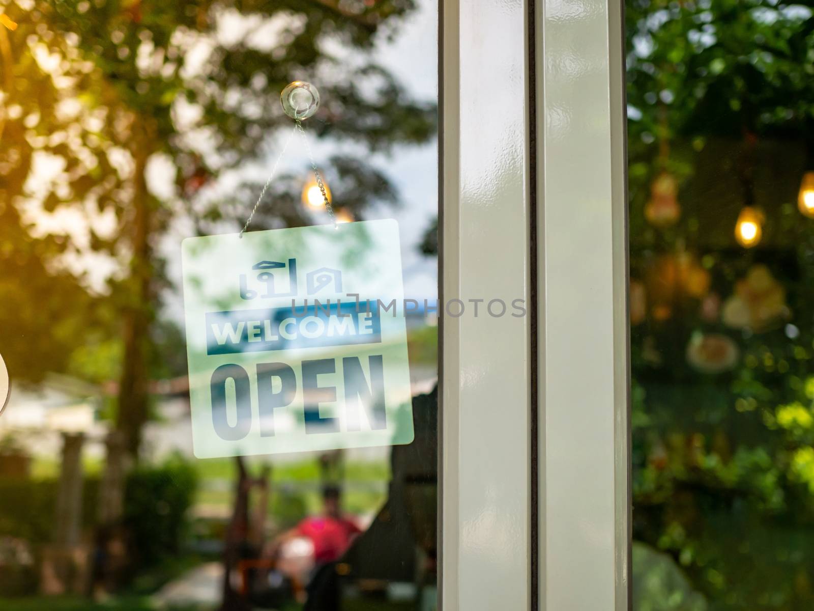 An open sign hangs behind the glass of a shop door. The idea of  by Unimages2527