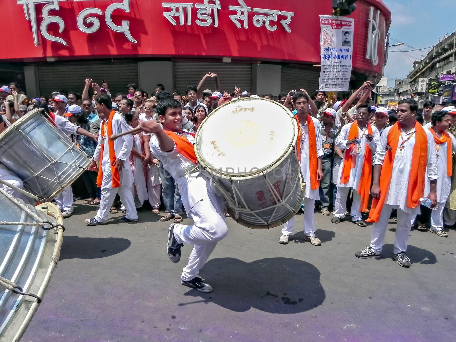Pune,Maharashtra,India-September 22nd,2010: Youth beating huge traditional dhol during festival procession of ganesh as people in crowd watch.
