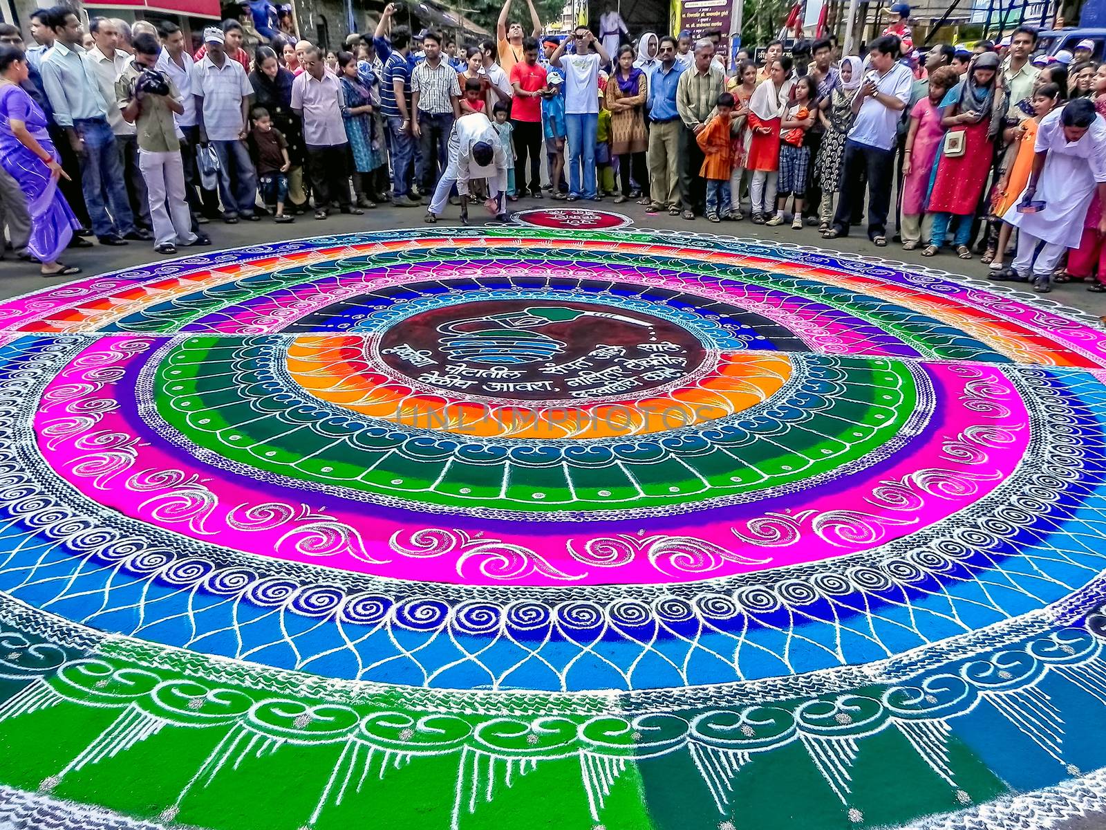 Artists drawing huge, traditional, colorful rangoli before arrival of Lord ganesh. by lalam
