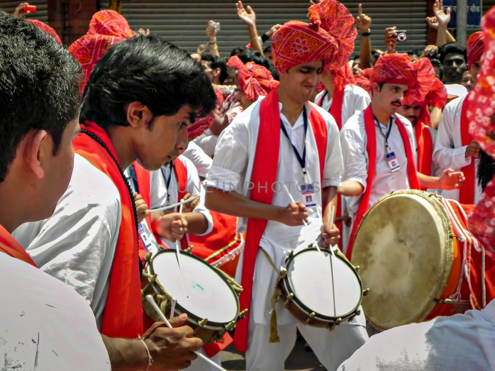 Pune,Maharashtra,India-September 22nd,2010: Group of youths beating traditional dhol & tasha collectively during festival procession of ganesh as people in crowd watch.