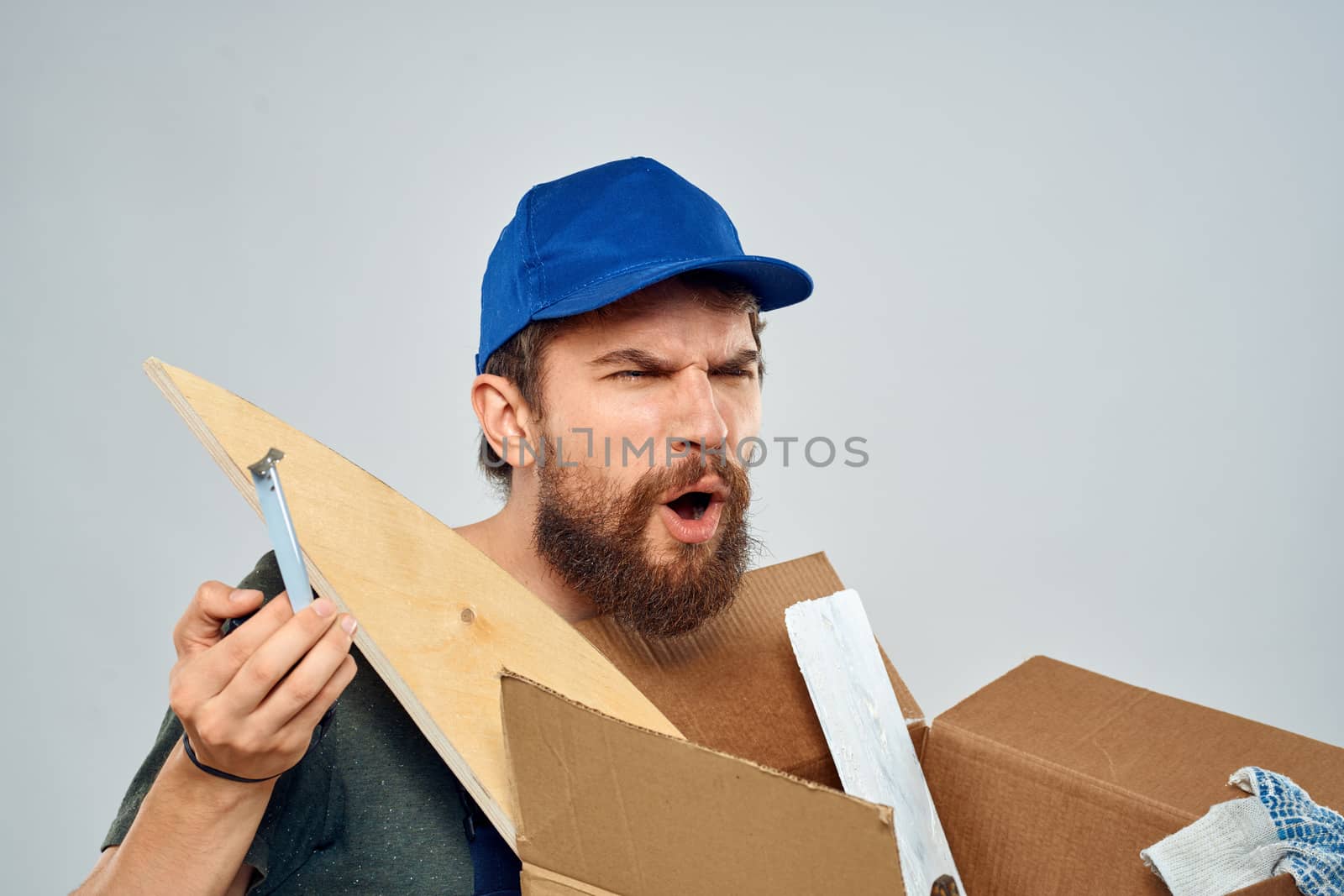 man in work uniform with box in hands tools lifestyle light background. High quality photo