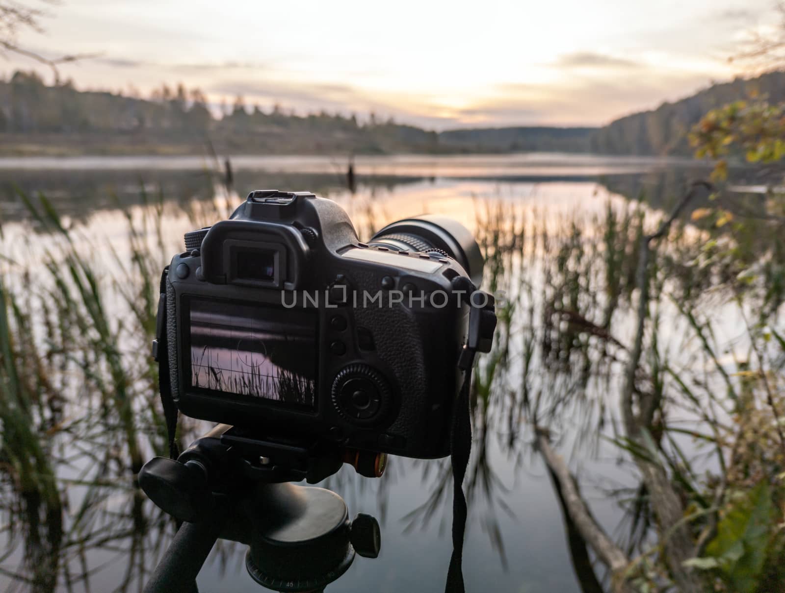 black digital camera on tripod shooting early foggy morning landscape at autumn lake with selective focus by z1b