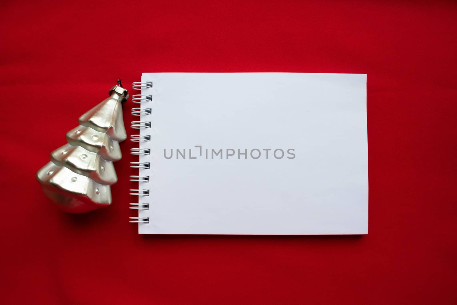 Notebook and silver Christmas tree on a red background. The concept of a New year.