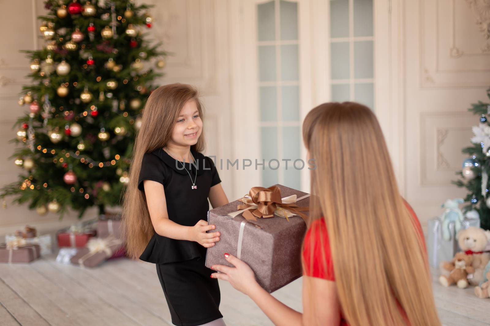 Little girl gives her mom a box with a Christmas present.