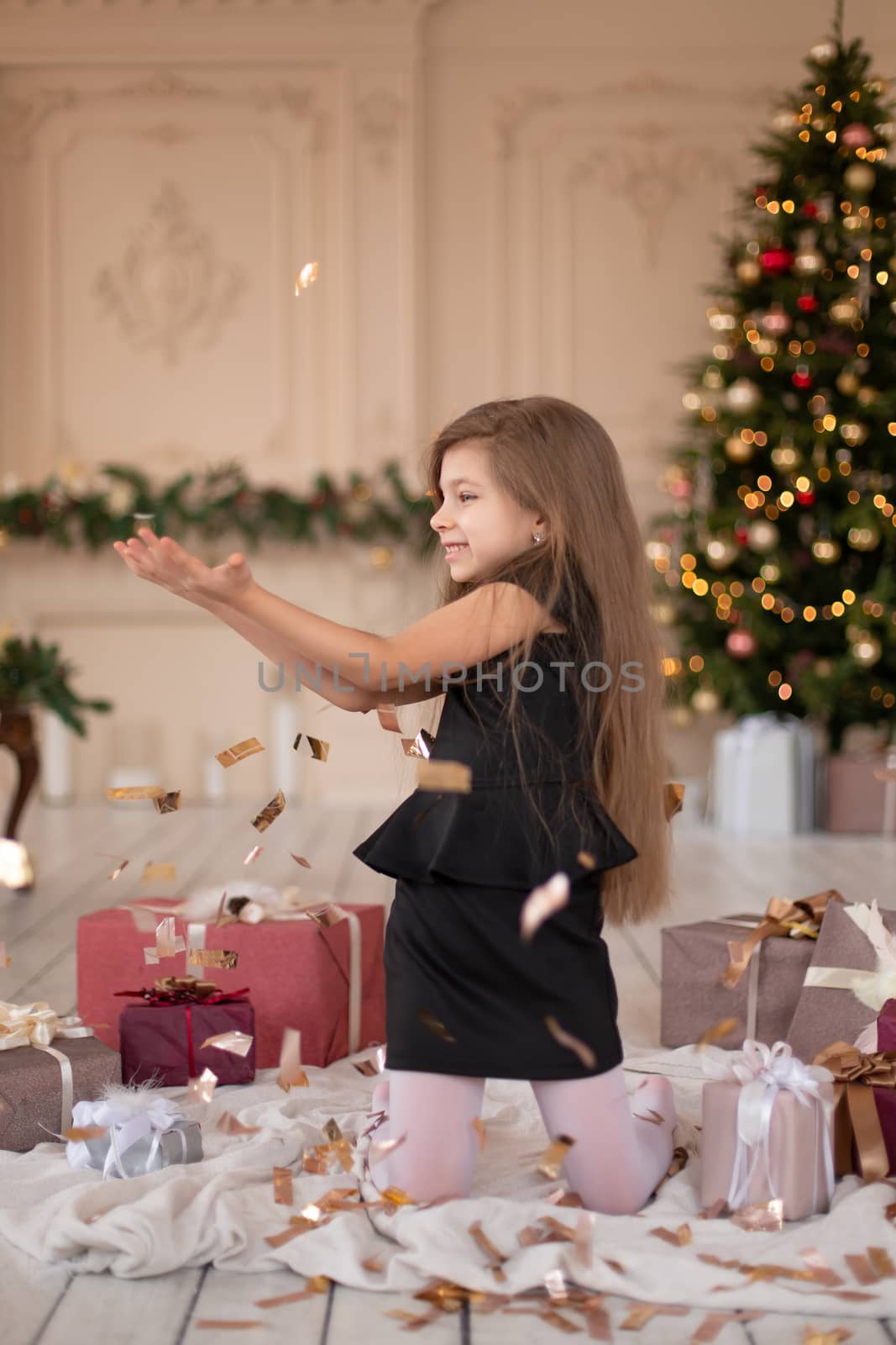 Little girl throws confetti. Christmas magic. Joyful moments of a happy childhood.